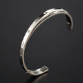 Open-ended stainless steel bracelet with zircon stones in gold, rose, or silver colour on a wrist.