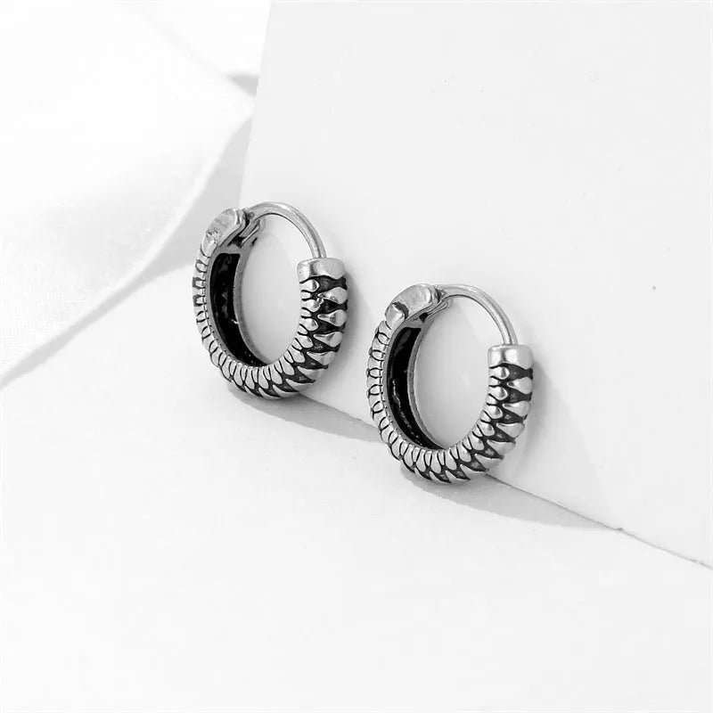 Silver geometric circular earrings made from twisted stainless steel stripes on a white background.