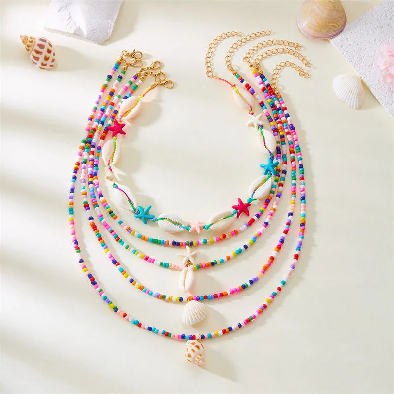 Blue multi-layer women's necklace set with starfish, shell, and conch bead pendants on bead chains