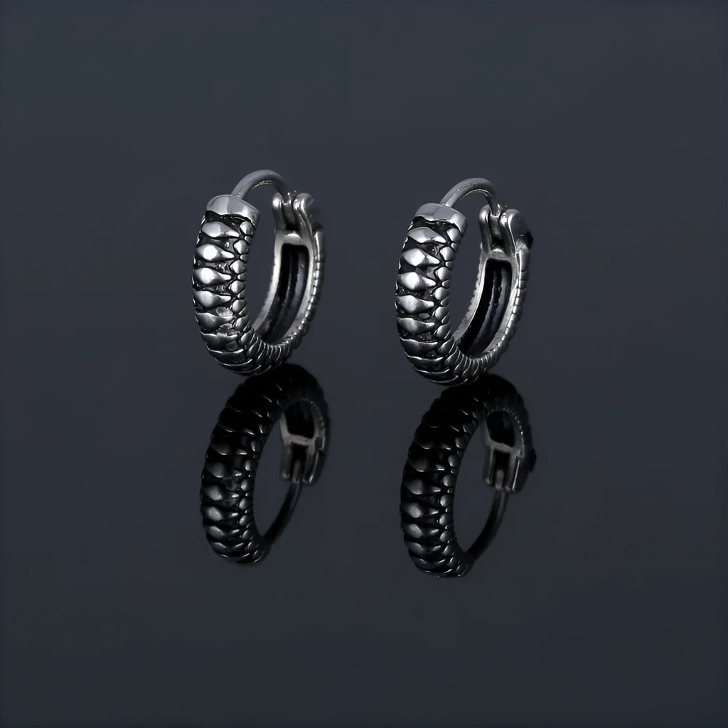 Silver geometric circular earrings made from twisted stainless steel stripes on a white background.
