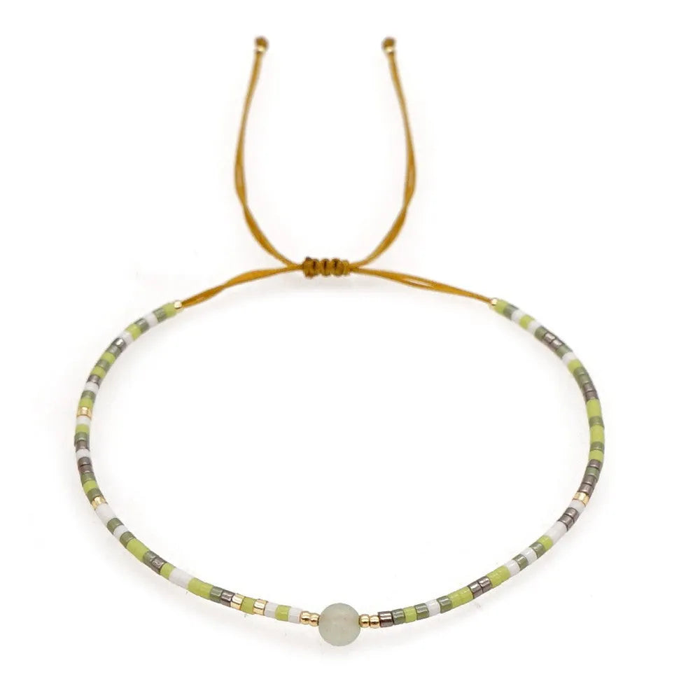 Close-up of a handmade Bohemian women's bracelet with colourful semi-precious stone and glass beads on a geometric string.
