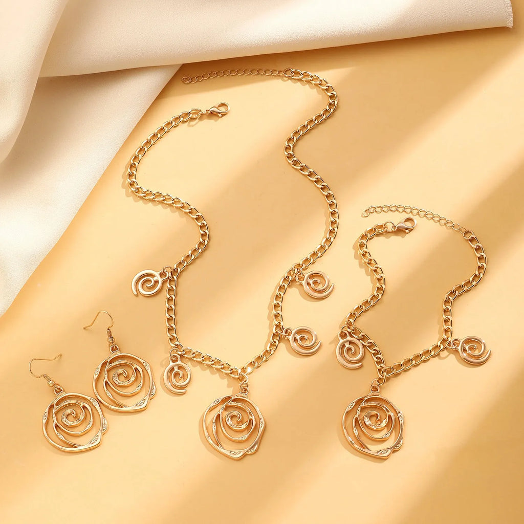 Women's spiral donut charm jewellery set with gold necklace, bracelet and earrings on white background