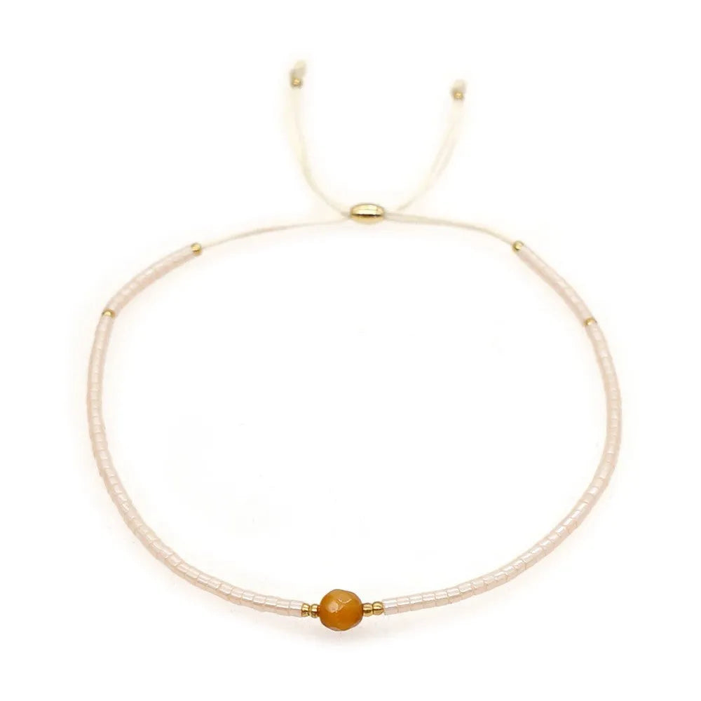 Close-up of a handmade Bohemian women's bracelet with colourful semi-precious stone and glass beads on a geometric string.