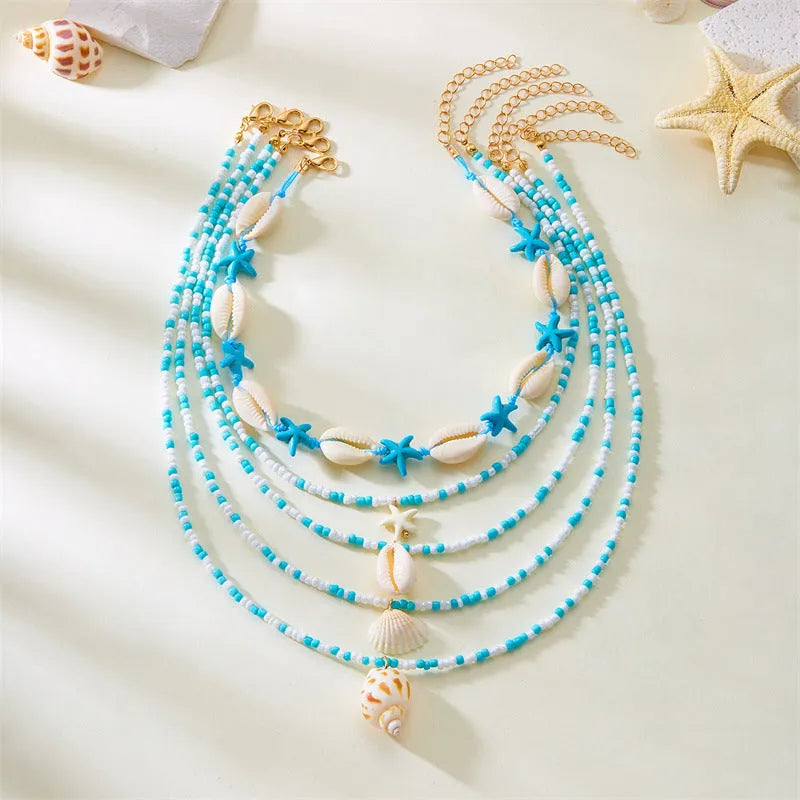 Blue multi-layer women's necklace set with starfish, shell, and conch bead pendants on bead chains
