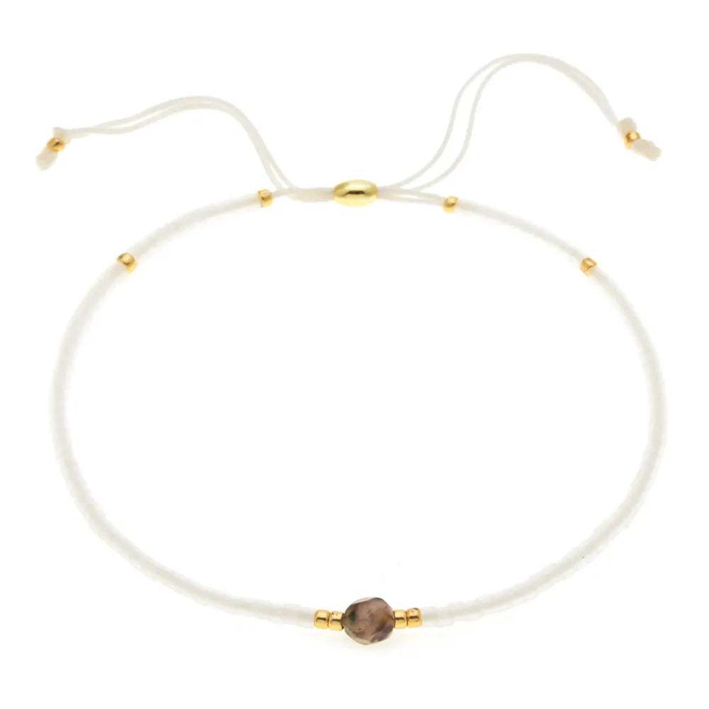 Close-up of a handmade Bohemian women's bracelet with colourful semi-precious stone and glass beads on a geometric string.