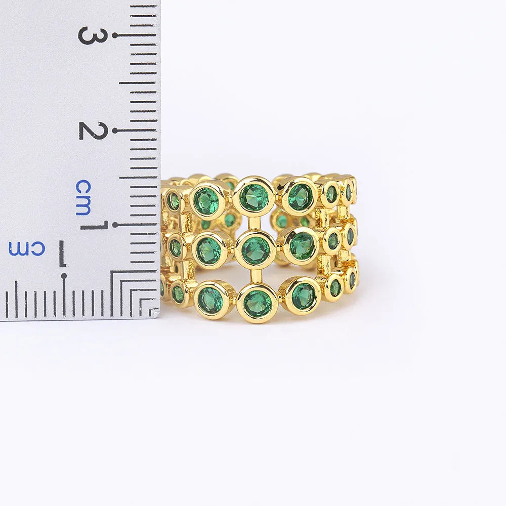 Wide band ring with gold plating and exaggerated green zircon detailing on copper base