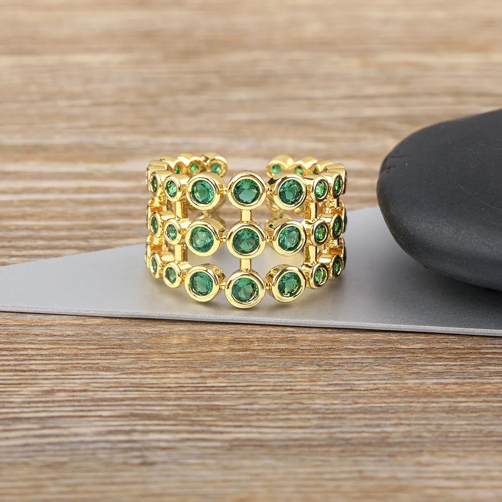 Wide band ring with gold plating and exaggerated green zircon detailing on copper base