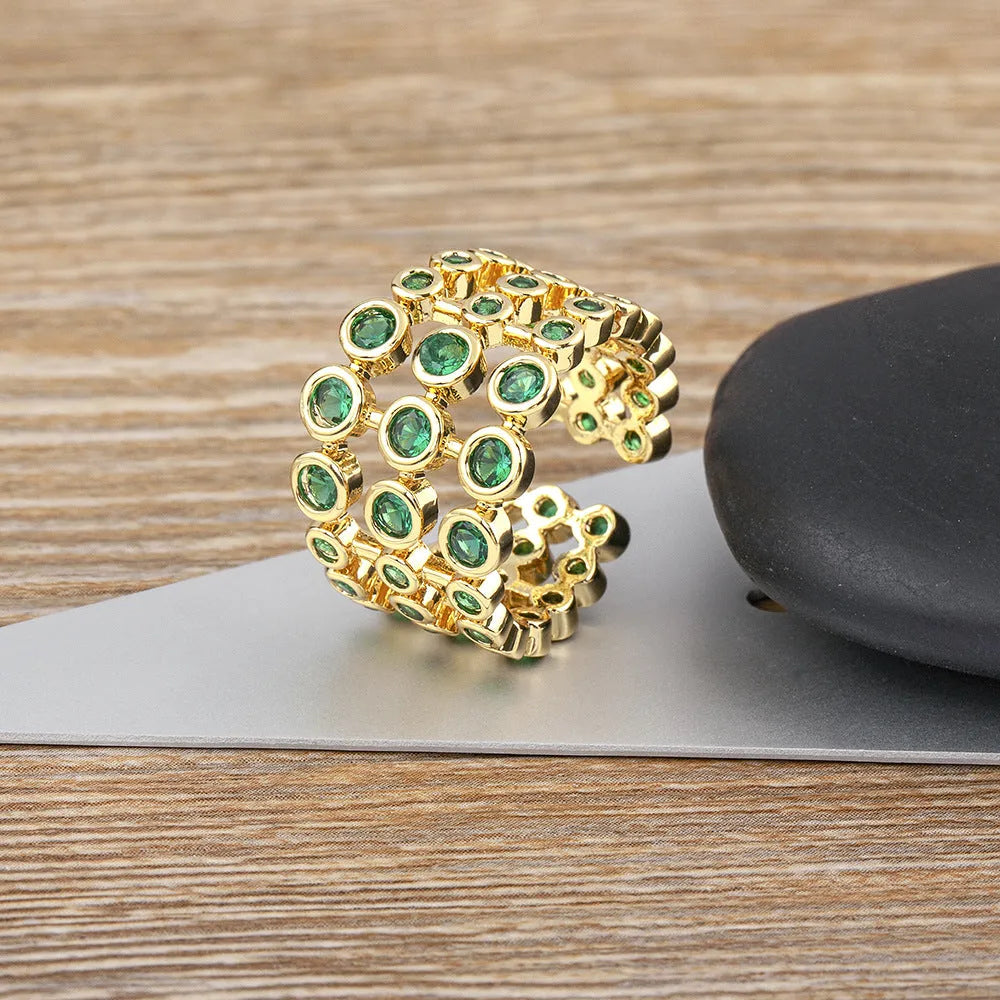 Wide band ring with gold plating and exaggerated green zircon detailing on copper base