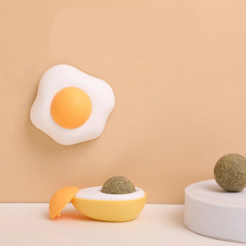 Interactive catnip ball toy stuck to wall with cat playing, showing fried egg and poached egg shape options