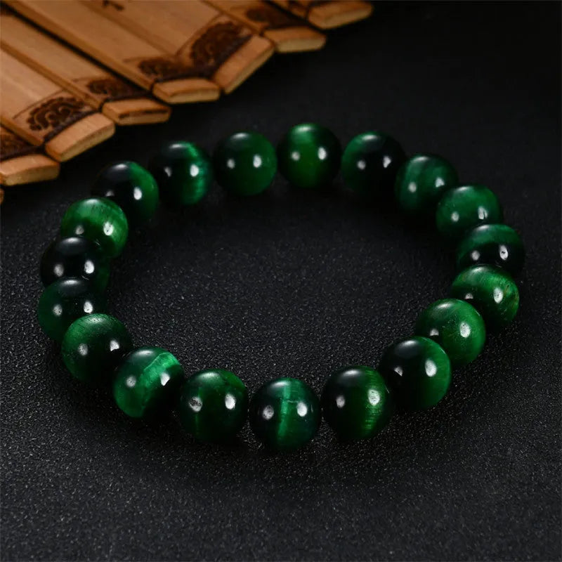 Green tiger eye stone bracelet with polished geometric beads on a wrist.