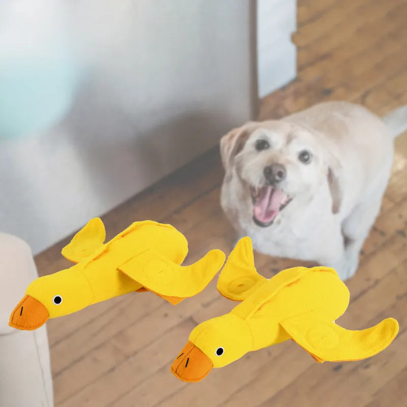 Yellow plush duck dog toy with squeaker and treat-dispensing feature for training and play.