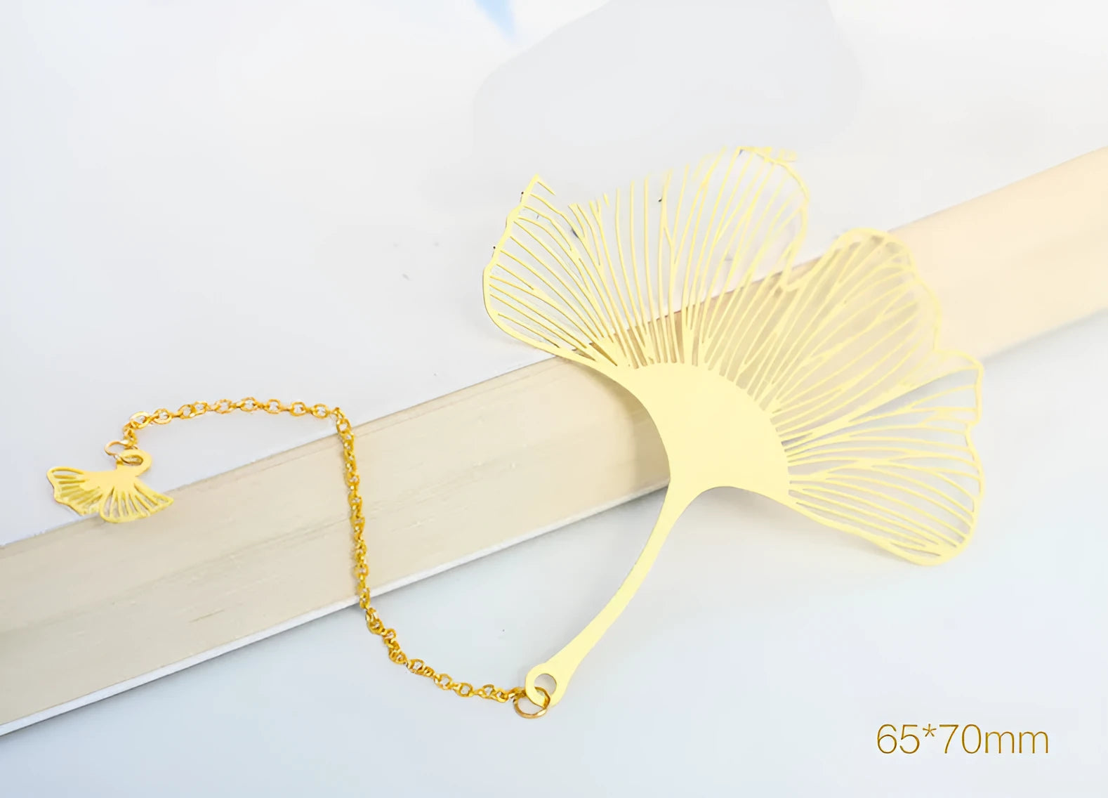 Brass metal bookmark with hollow leaf design and rose gold tassel in a presentation box.