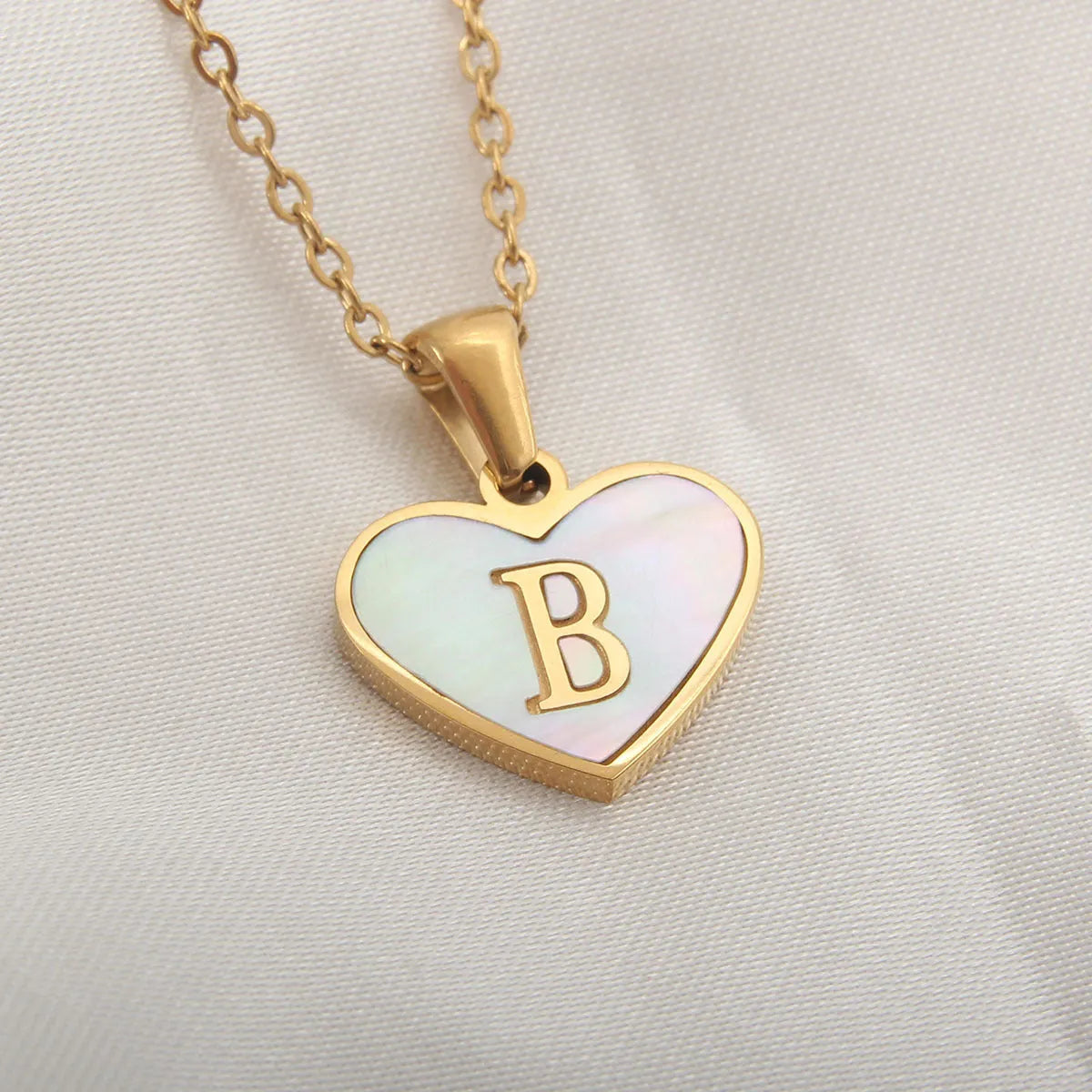 Gold plated heart-shaped necklace with a personalised initial letter and white shell detail on a 50cm adjustable chain.
