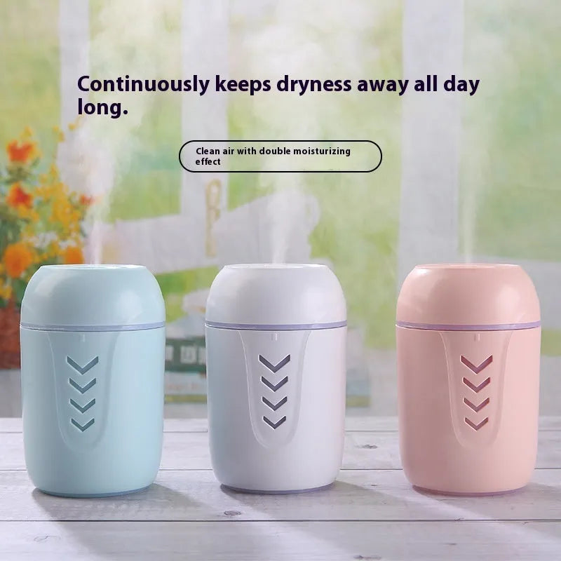 Round white portable air purifier with USB cable on a wooden desk.