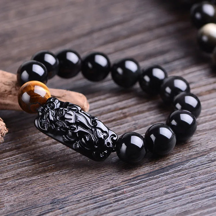 Natural obsidian carved Pi Xiu bracelet with black beads on a cord, gift box and bag visible