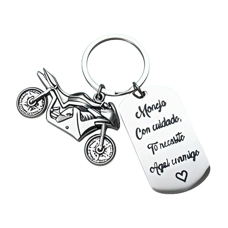 Silver motorcycle charm on a stainless steel key ring next to a red flannel storage bag.