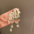 Gold long drop earrings with pearl, bow, tassel, and sequin detail on white background