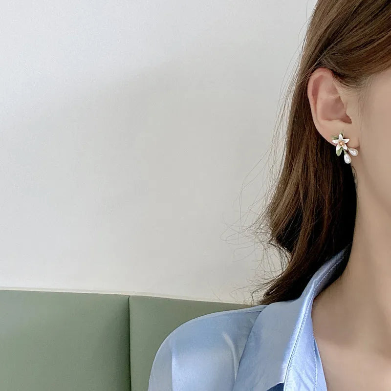 A pair of alloy camellia flower earrings for women, showing both the stud and clip styles.