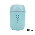 Round white portable air purifier with USB cable on a wooden desk.