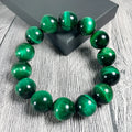 Green tiger eye stone bracelet with polished geometric beads on a wrist.