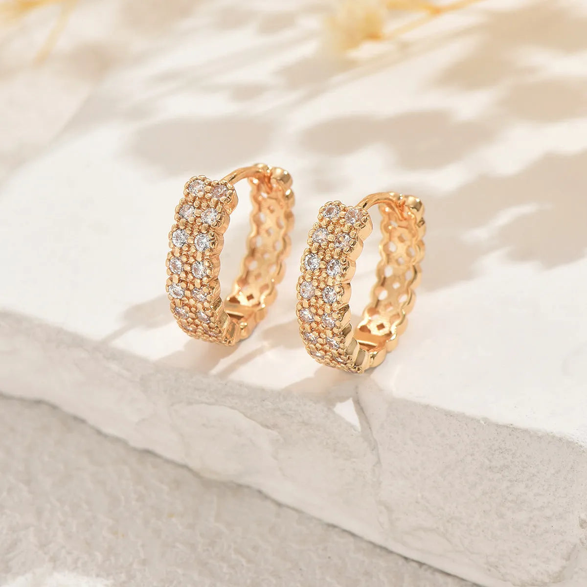A pair of geometric pattern copper ear studs with round, dot, and ring design details.