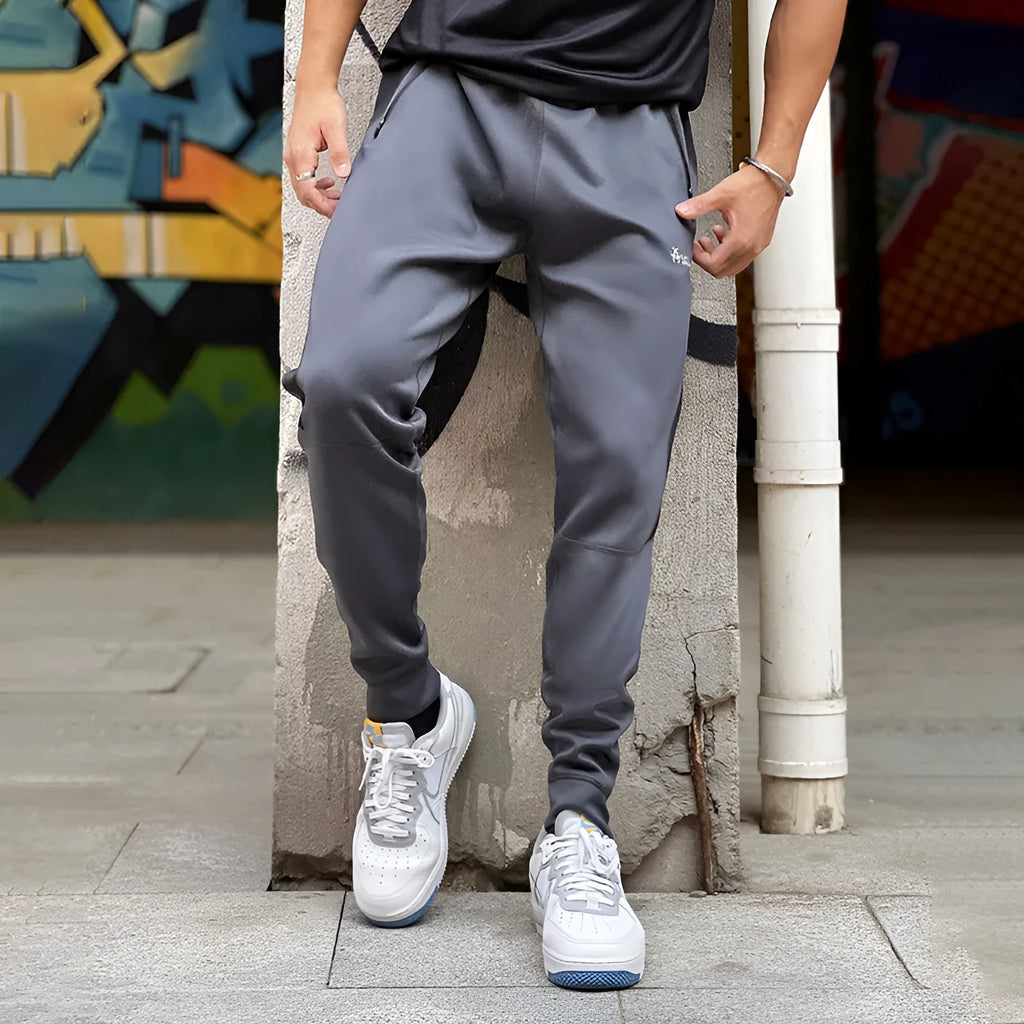 Men's deep gray stretch polyester sweatpants with panel zip pockets, side view