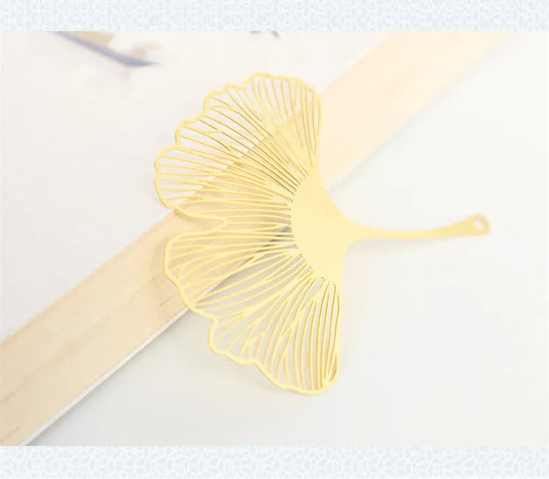 Brass metal bookmark with hollow leaf design and rose gold tassel in a presentation box.