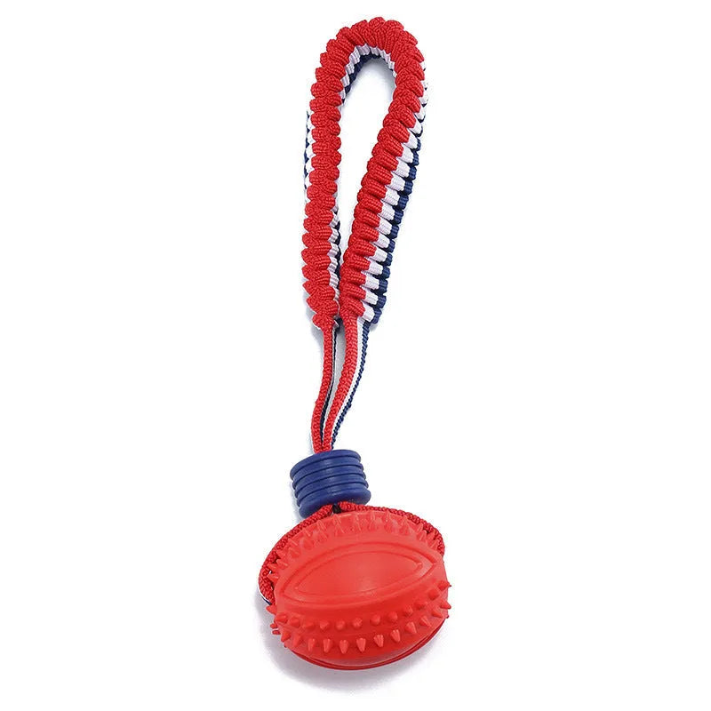 Blue dog toy with a textured rubber ball attached to a cotton rope, shown on grass.