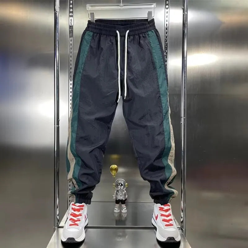 Men's loose fit contrast stripe jogger sports pants in black, showing drawstring waist and tapered leg