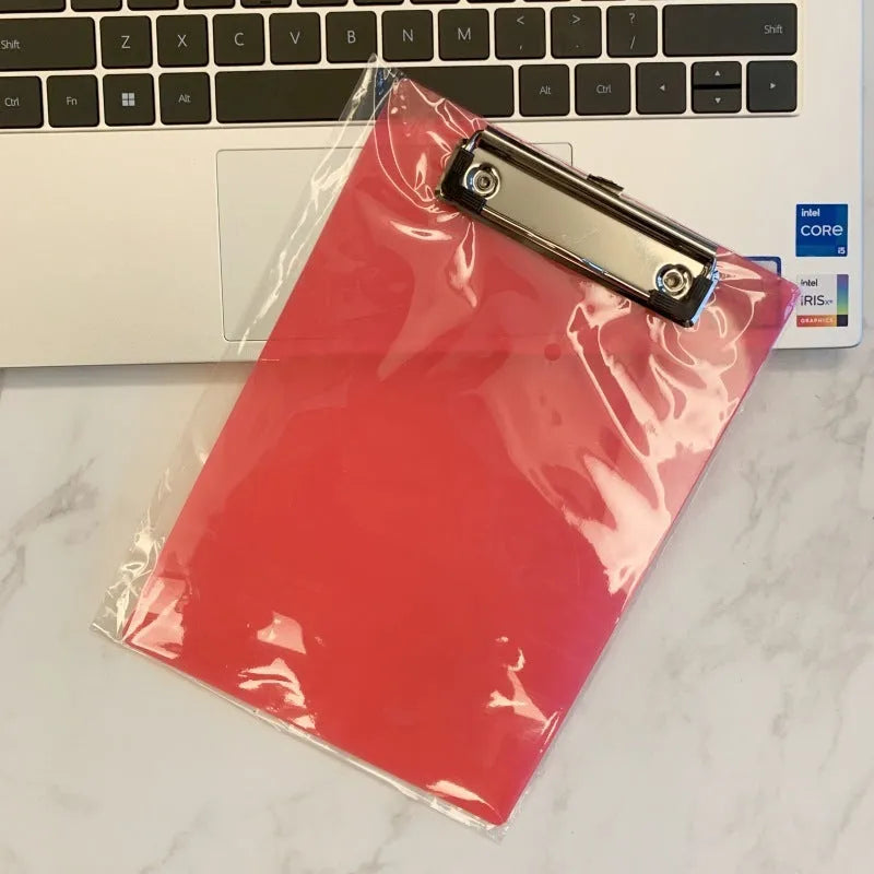 A4 transparent plate clipboard with metal clip, shown in blue colour on a desk with paper.