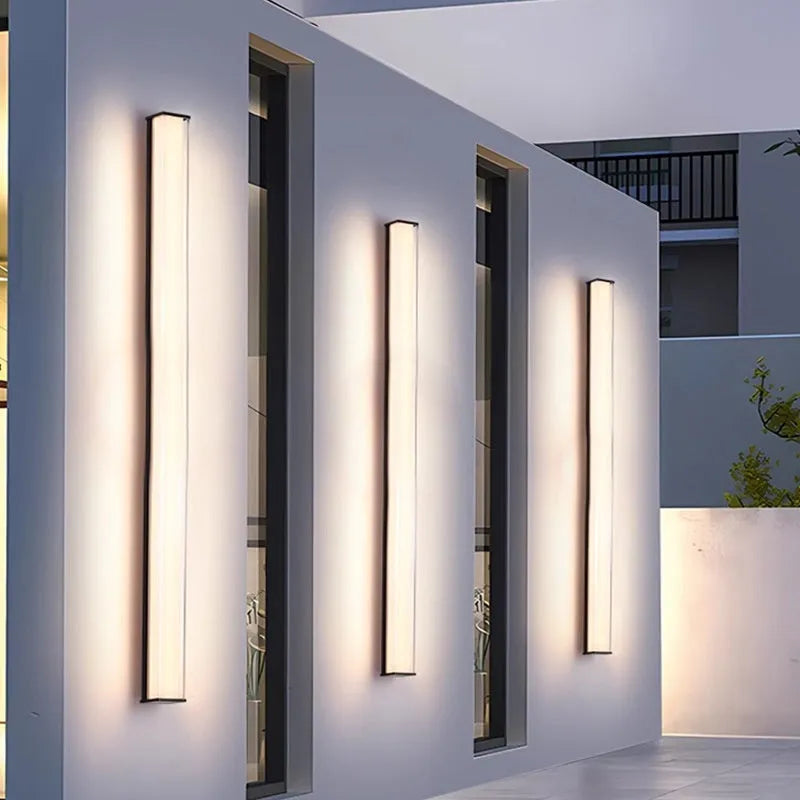 Modern outdoor wall lamp mounted on stone wall, showing clean lines and illuminated light source.