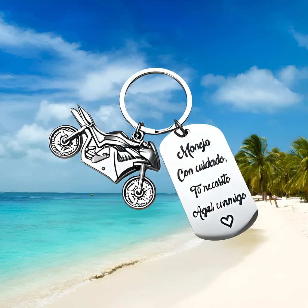 Silver motorcycle charm on a stainless steel key ring next to a red flannel storage bag.