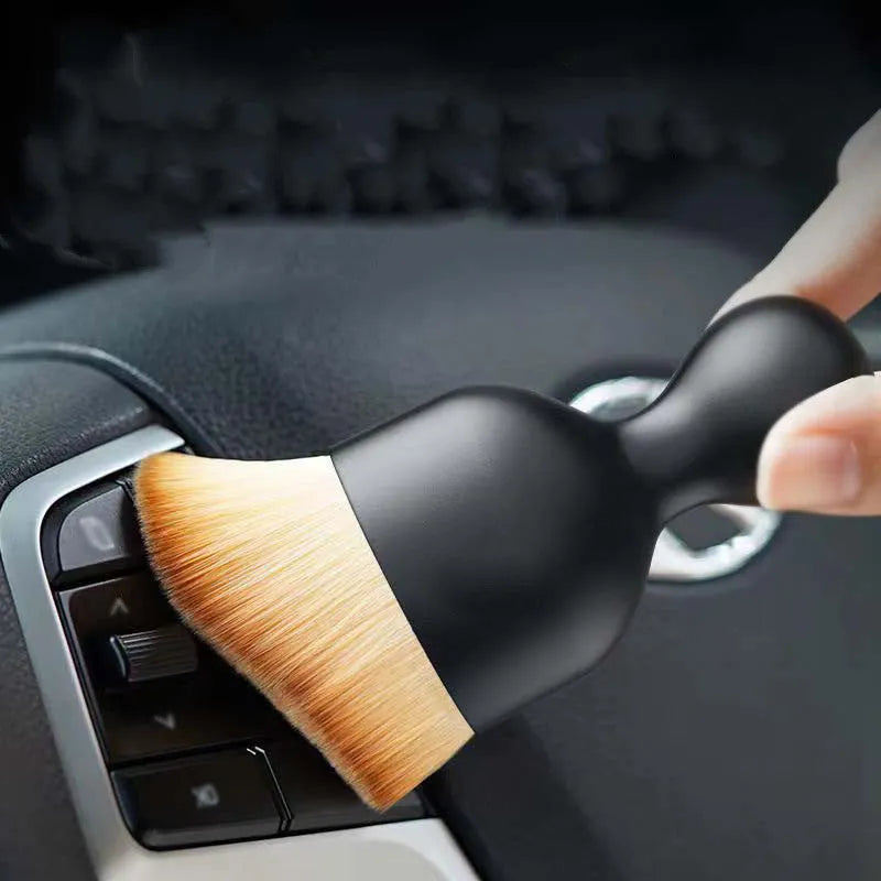 White PVC car interior cleaning brush on a car dashboard, showing its compact size and soft bristles.