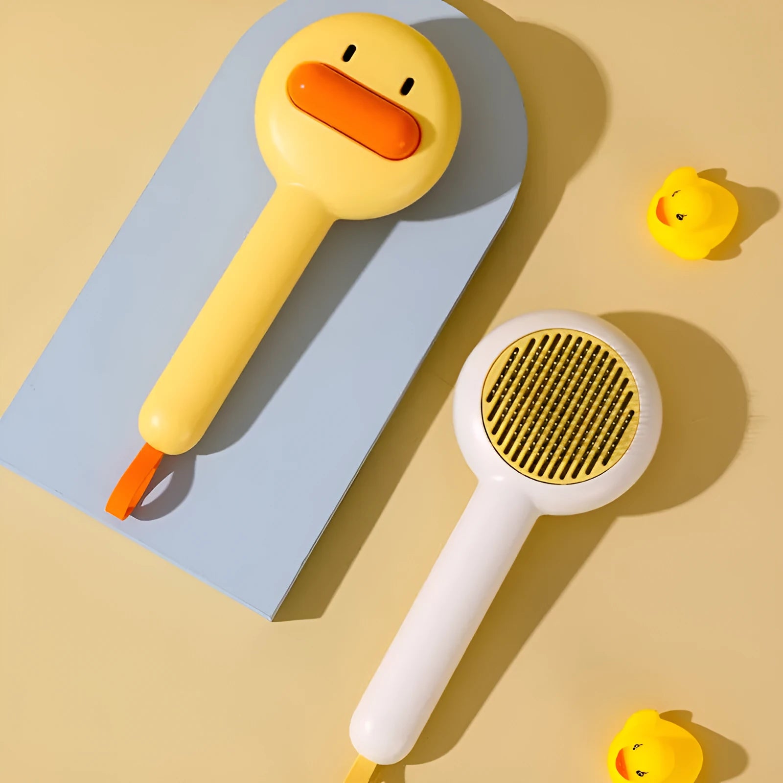 Small plastic pet comb with yellow duck design, showing open sections and floating needles for cat and dog grooming.