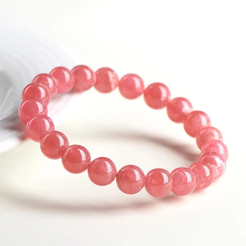 Women's red rhodochrosite crystal bracelet with geometric beads and a longevity lock clasp on a wrist.