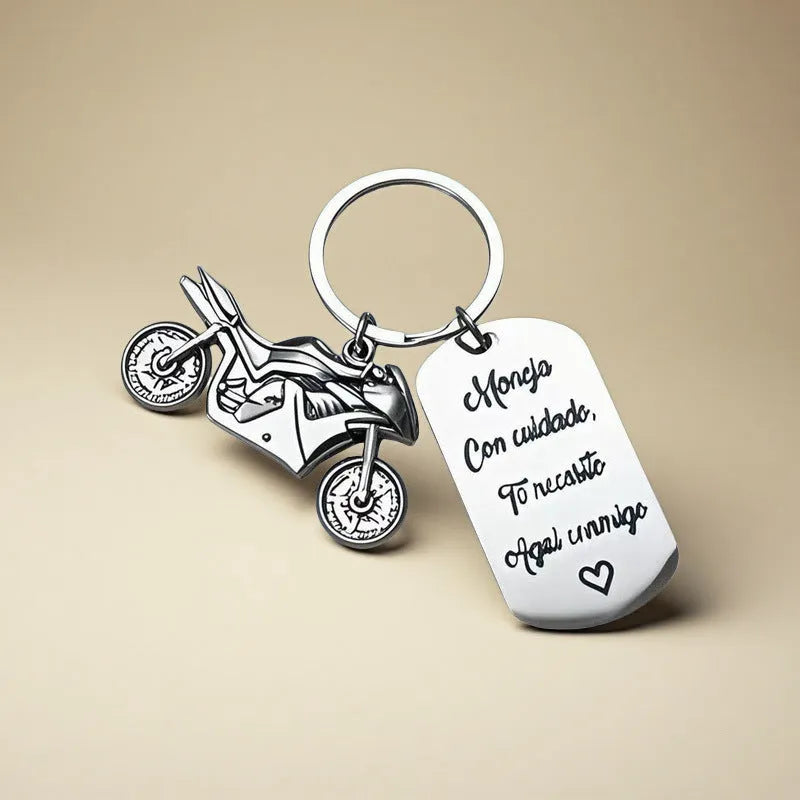 Silver motorcycle charm on a stainless steel key ring next to a red flannel storage bag.