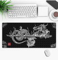 Large black gaming mouse pad with an anime character print, lying flat on a wooden desk.