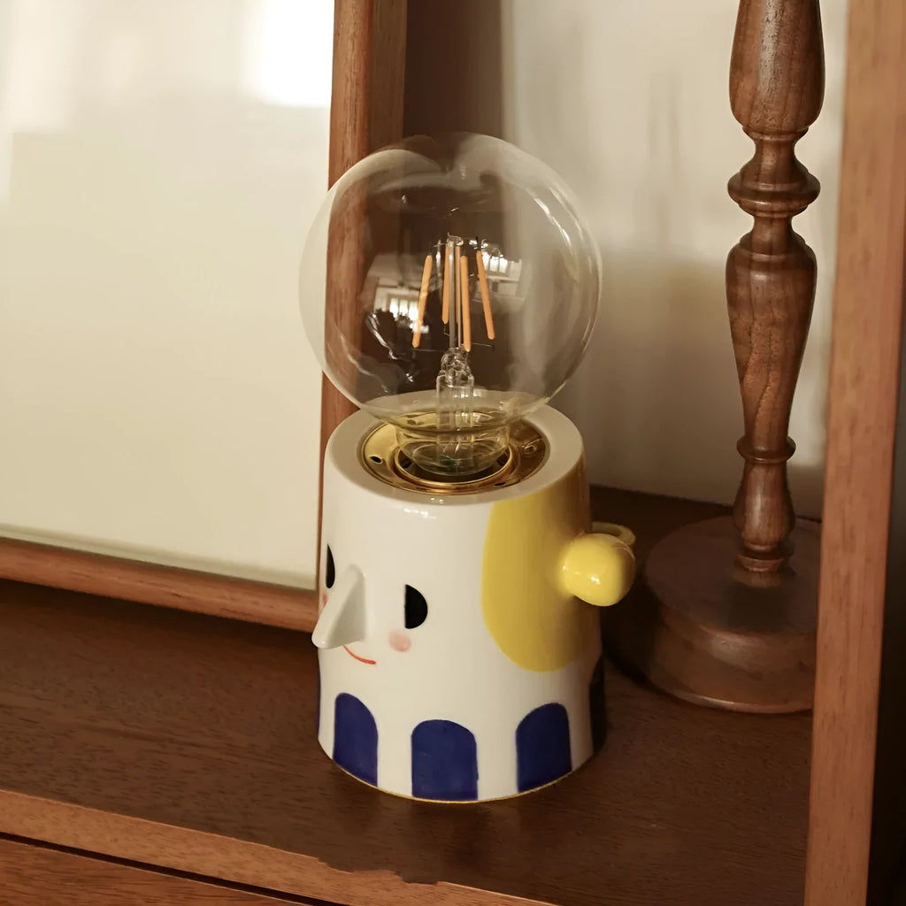 Handmade ceramic bedside lamp with ball headlight colour design on a table.