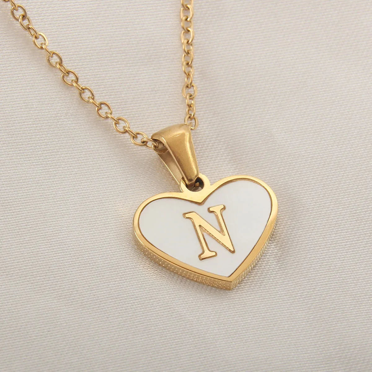 Gold plated heart-shaped necklace with a personalised initial letter and white shell detail on a 50cm adjustable chain.