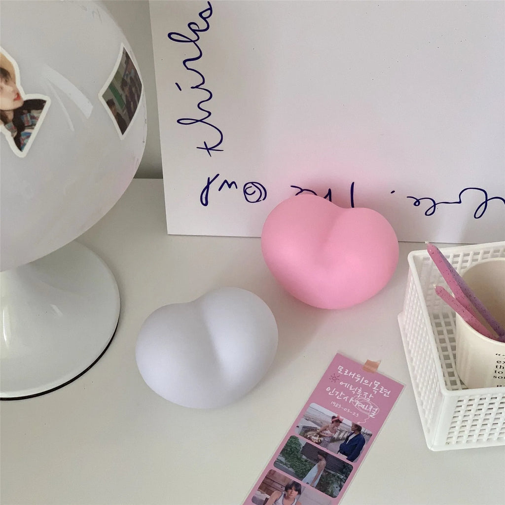Small pink vinyl atmosphere lamp glowing with warm light on a wooden surface.