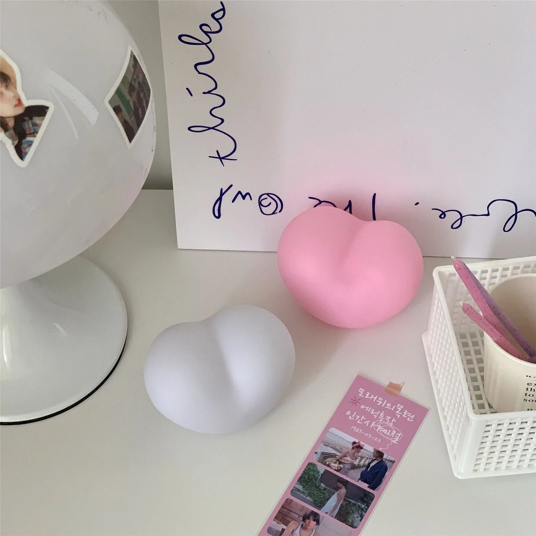 Small pink vinyl atmosphere lamp glowing with warm light on a wooden surface.