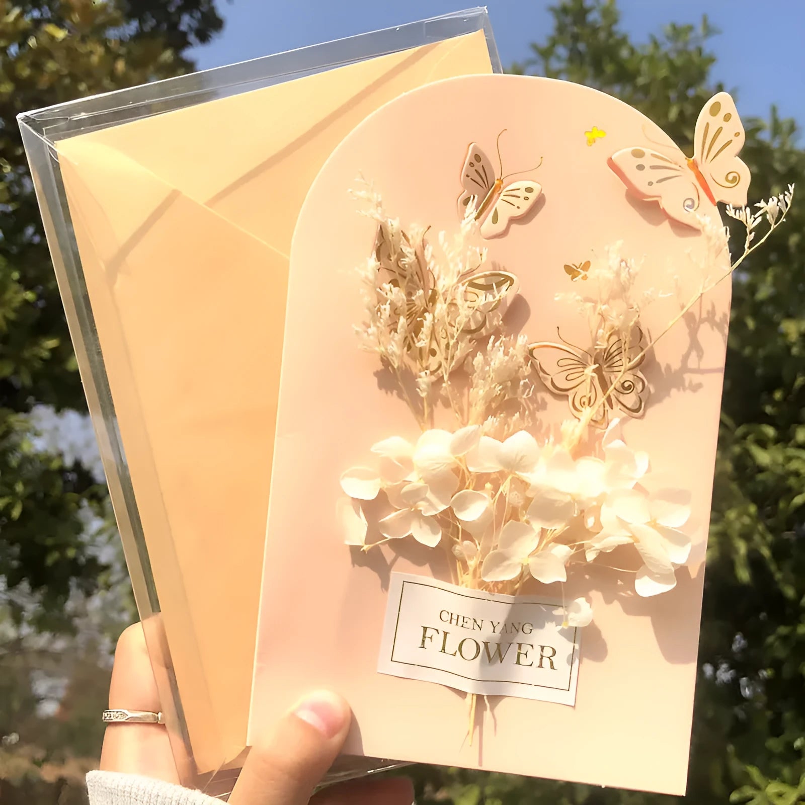 Handmade 3D boxed greeting card with butterfly shape, hot stamping, and artificial flowers on coated paper.