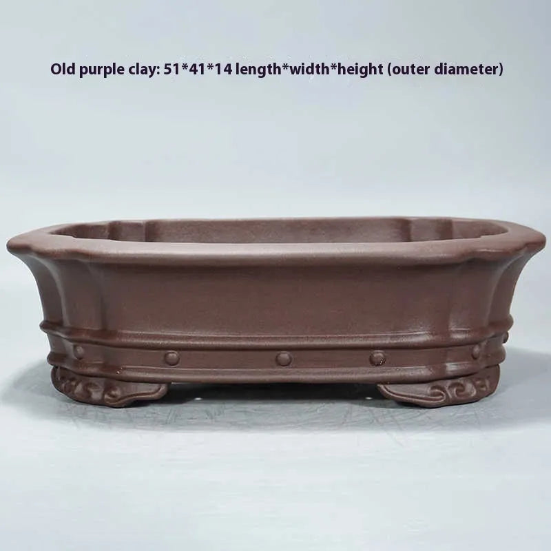 Purple clay handmade rectangular flower pot with antique design on wooden desktop