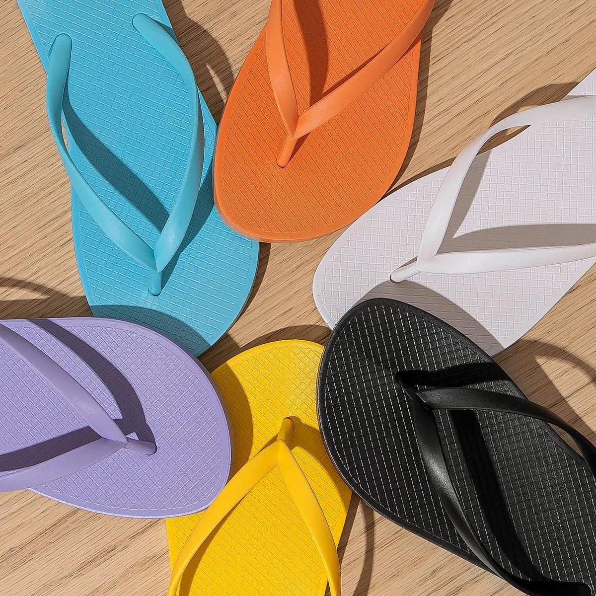 Foldable flat slippers with non-slip PVC sole and plastic upper in orange, purple, black, or white.