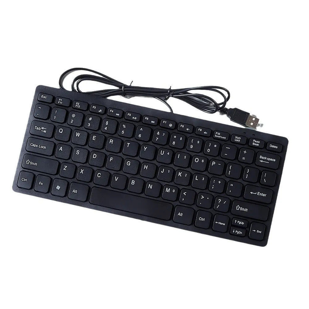 Compact wired USB keyboard in black, white, pink, or blue on a desk next to a laptop.