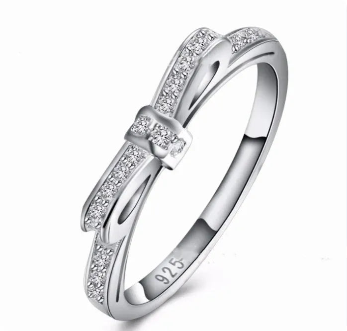 Silver bow-shaped ring with rhinestone detailing, shown in electroplated finish