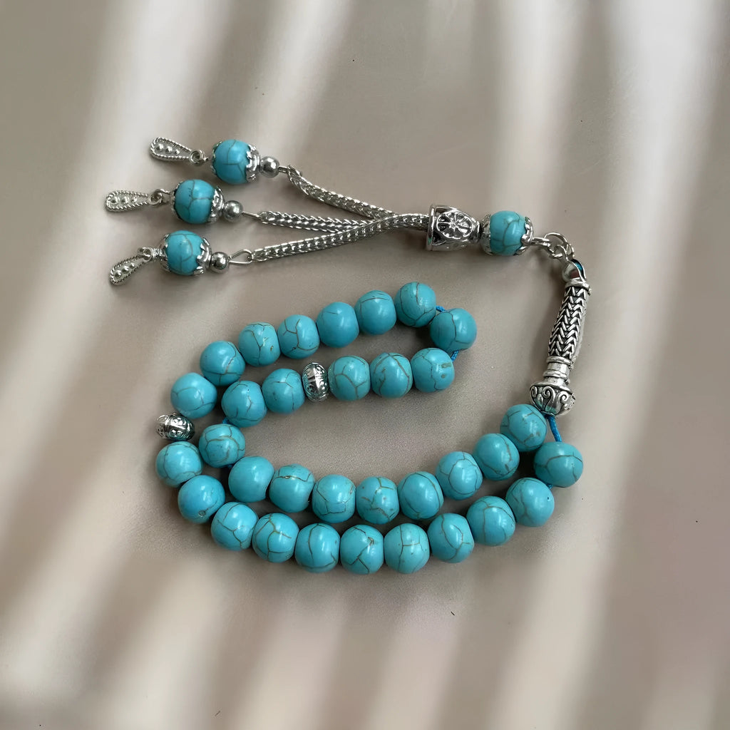 Sky blue stone bead Muslim prayer bracelet with sliding knot on a wrist.