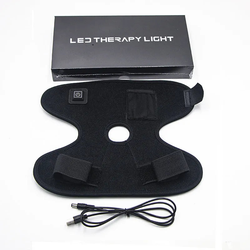 Black ankle heating wrap with red light therapy and USB cable on flat surface