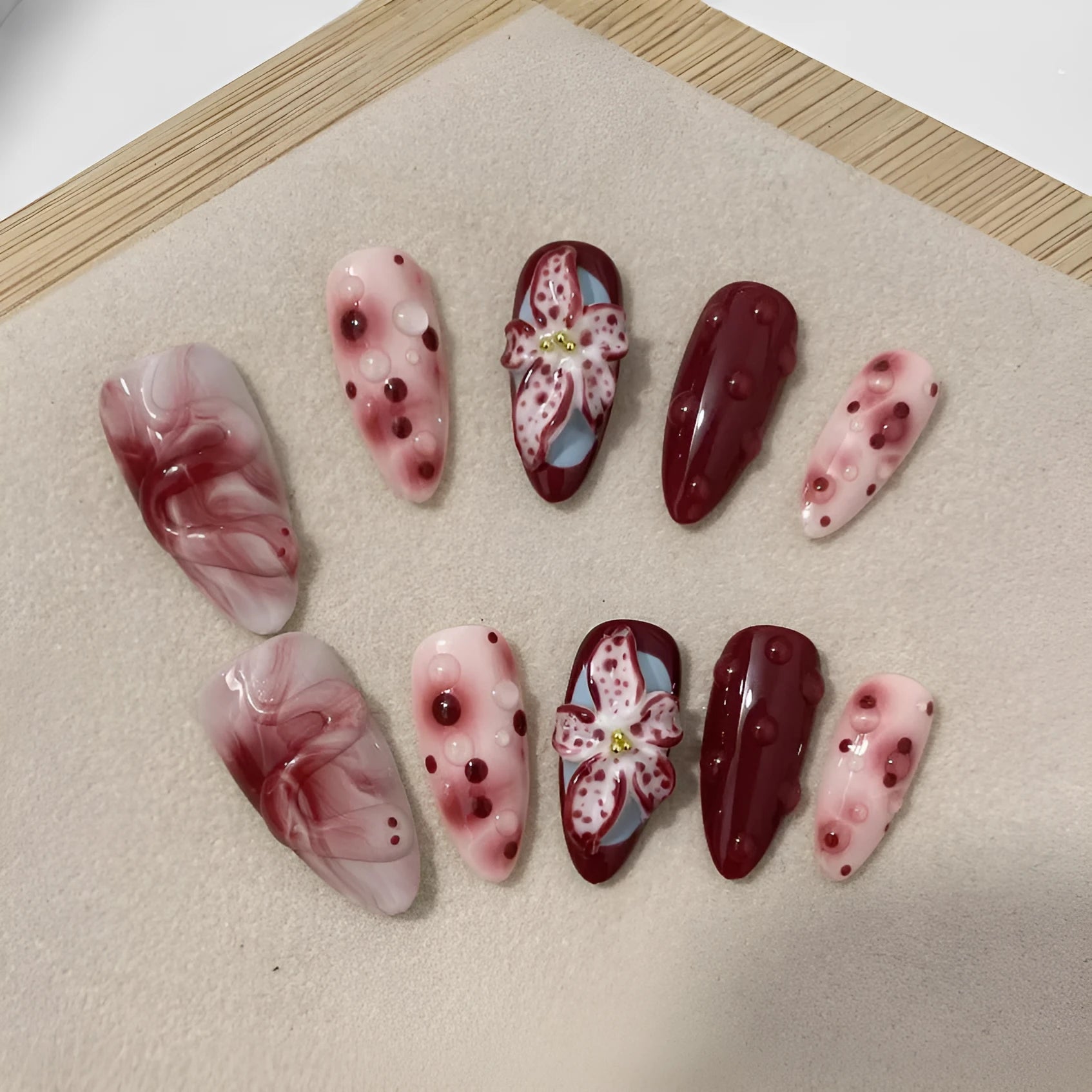 Hand-painted three-dimensional carved acrylic manicure nails in almond colour with floral and geometric patterns