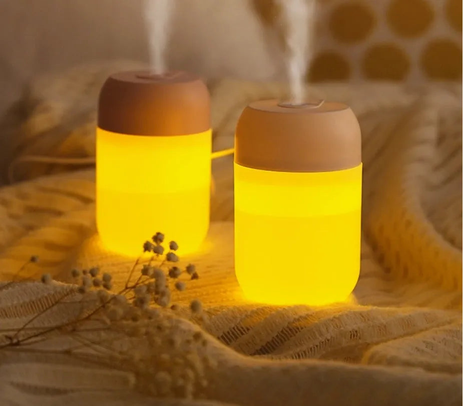 Small white cylindrical USB humidifier with aromatherapy function on a wooden desk.